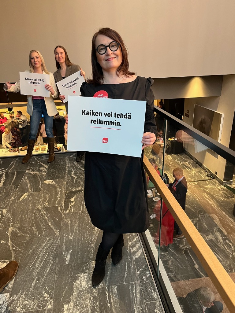 Vantaan valtuuston puheenjohtaja, kuntavaaliehdokas Säde Tahvanainen, SDP:n kampanja-avauksessa Vantaalla 8.2.2025, nostaa pitää kädessään SDP:n kampanja slogan kylttiä jossa lukee kaiken voi tehdä reilummin.